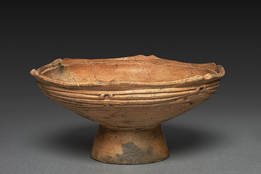 Hand-built Jōmon period ceramic container showing the characteristic cord-wrapped decorative impressions and asymmetrical flared edge