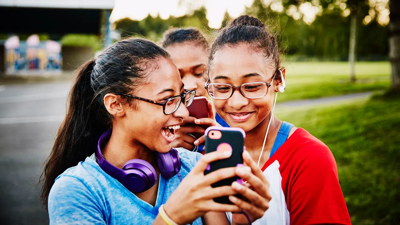 Teenagers using social media on smartphones showing the pressure of online interactions