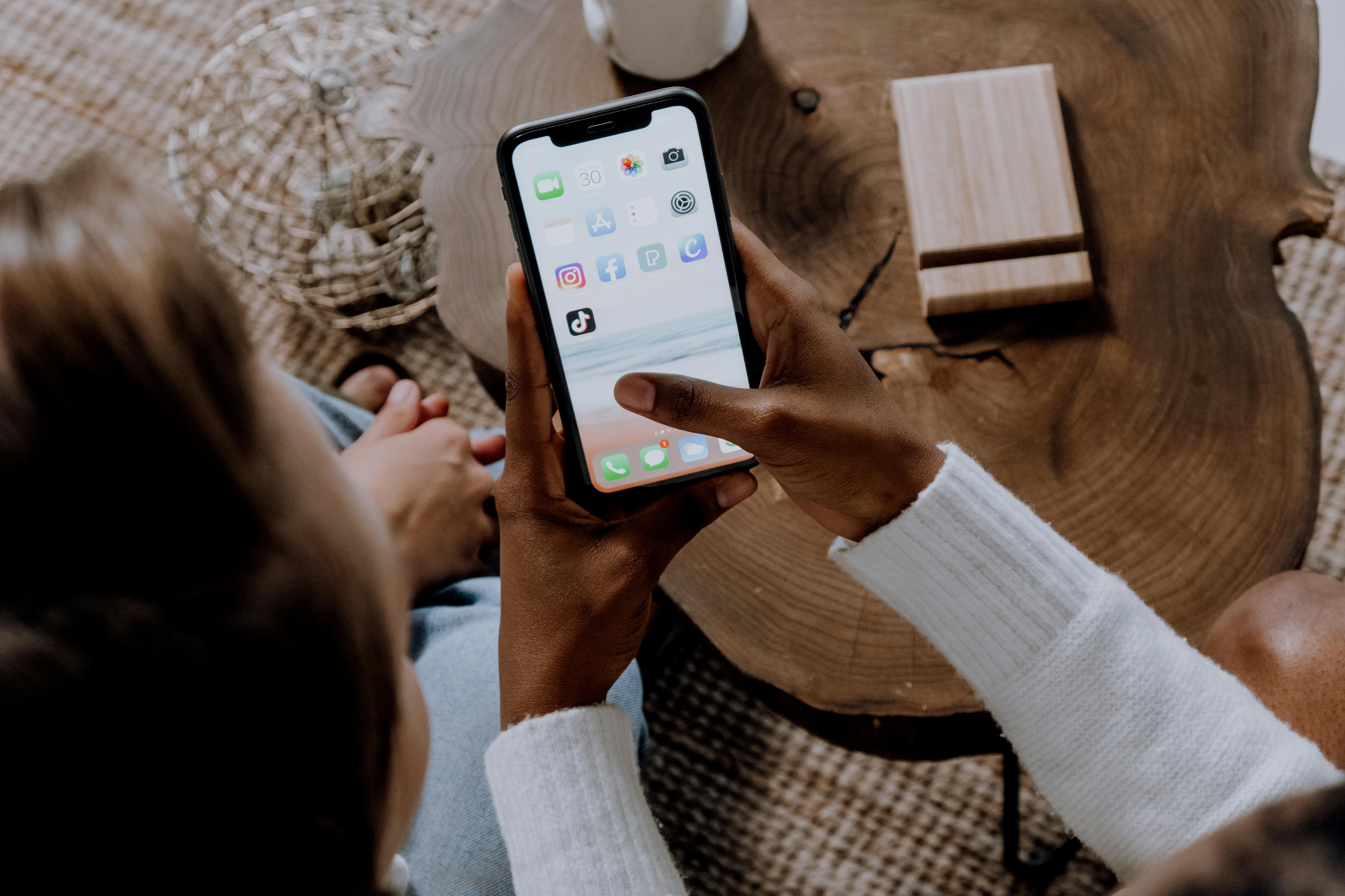Close-up of a hand holding a smartphone displaying social media apps like TikTok and Instagram, symbolizing digital engagement