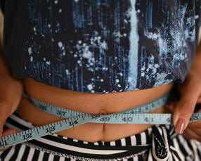 A lady measuring her waist with a measuring tape